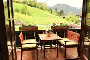 A balcony with wooden furniture, a table, and potted plants. - Holiday apartment with 3 bedrooms (Schönau am Königssee)