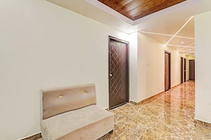 Un pasillo con un banco, una puerta de madera y suelo de mármol.