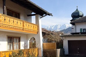A traditional building with a balcony, a garage, and a mountain backdrop. - Holiday apartment with 1 bedroom (Garmisch-Partenkirchen)