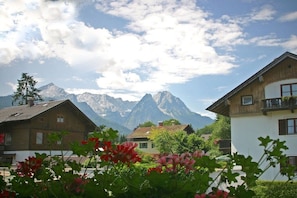A mountain village with traditional wooden houses, a clear sky, and a prominent mountain range in the background. - Holiday apartment with 1 bedroom (Garmisch-Partenkirchen)