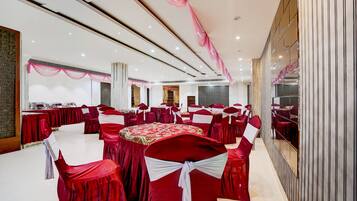 A banquet hall with round tables, red tablecloths, and chairs with white sashes.