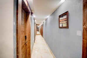 Un pasillo con puertas de madera, suelo de mármol y una obra de arte enmarcada en la pared.