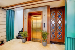 Un ascensor con pared texturizada y puerta de madera con paneles de vidrio en forma de diamante.