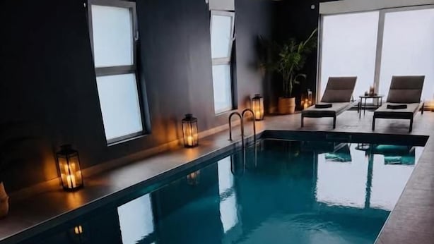 Una piscina con vistas al cielo, rodeada de ventanas y con faroles.