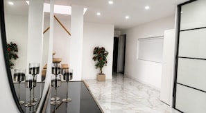 A modern interior with a glass table, potted plants, and a staircase.