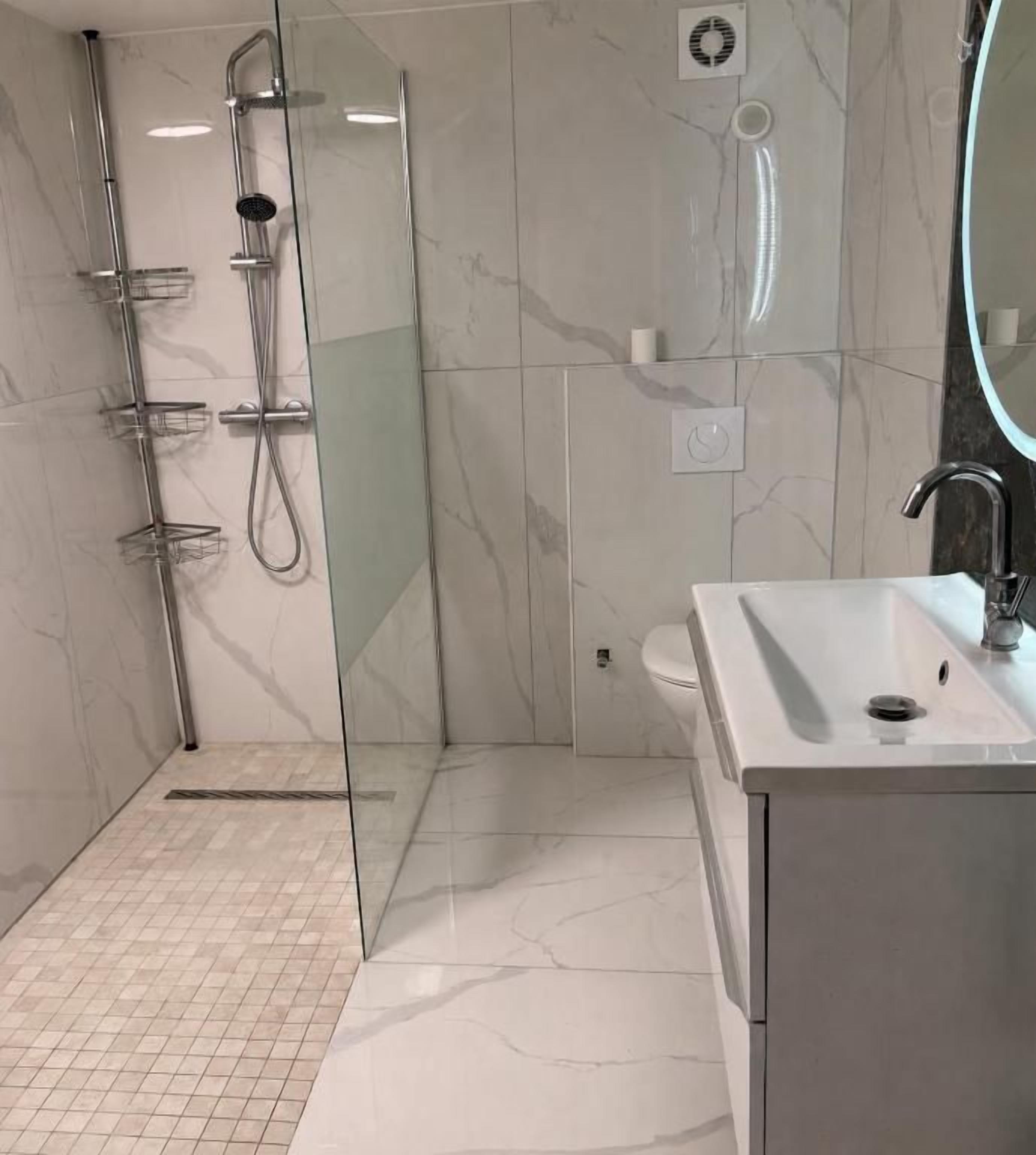 A modern bathroom with a glass-enclosed shower, a white sink, and a toilet.
