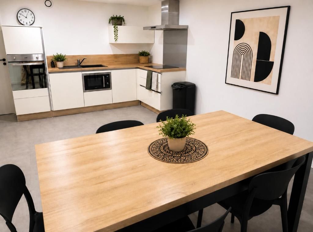 A modern kitchen with white cabinets, a wooden countertop, and a black trash bin.