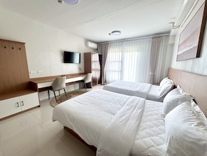 A hotel room with a bed, a desk, a chair, a television, and a wardrobe. - Royal Oceancrest Panglao 1 (Dauis)