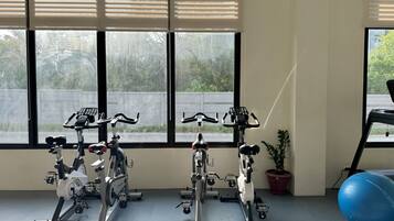 Una habitación con cuatro bicicletas estáticas, una pelota de ejercicios azul y una planta en maceta.
