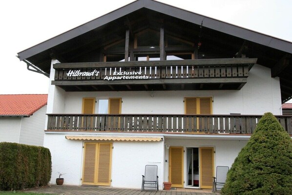Um edifício de dois andares com varanda e placa que diz 'Hilbrand's Exclusive Apartments'.