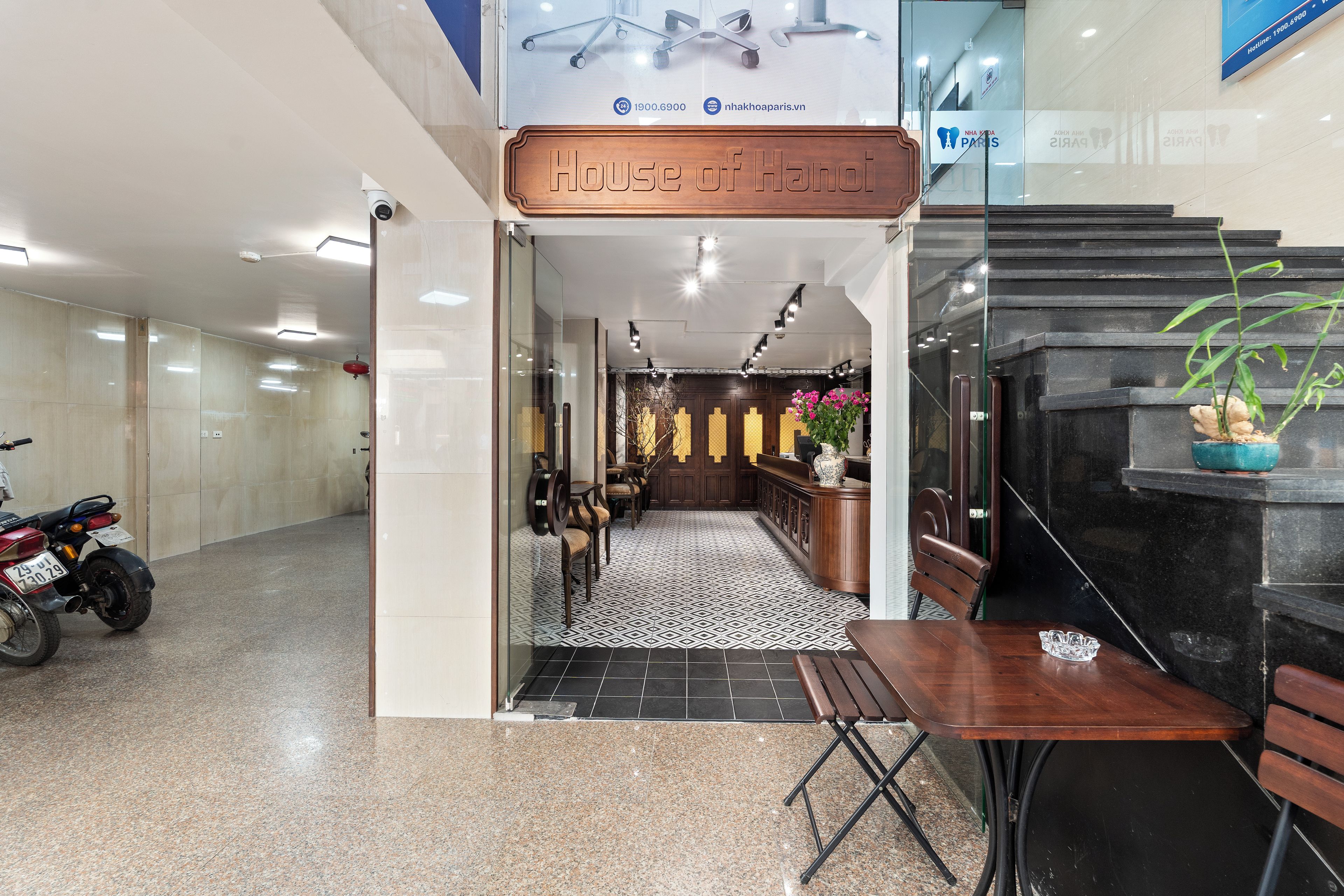 A hotel entrance with a reception desk, seating area, and a motorcycle parked outside.