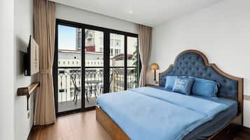 Habitación de hotel con una cama grande, un televisor en la pared y un balcón con vistas a la ciudad.