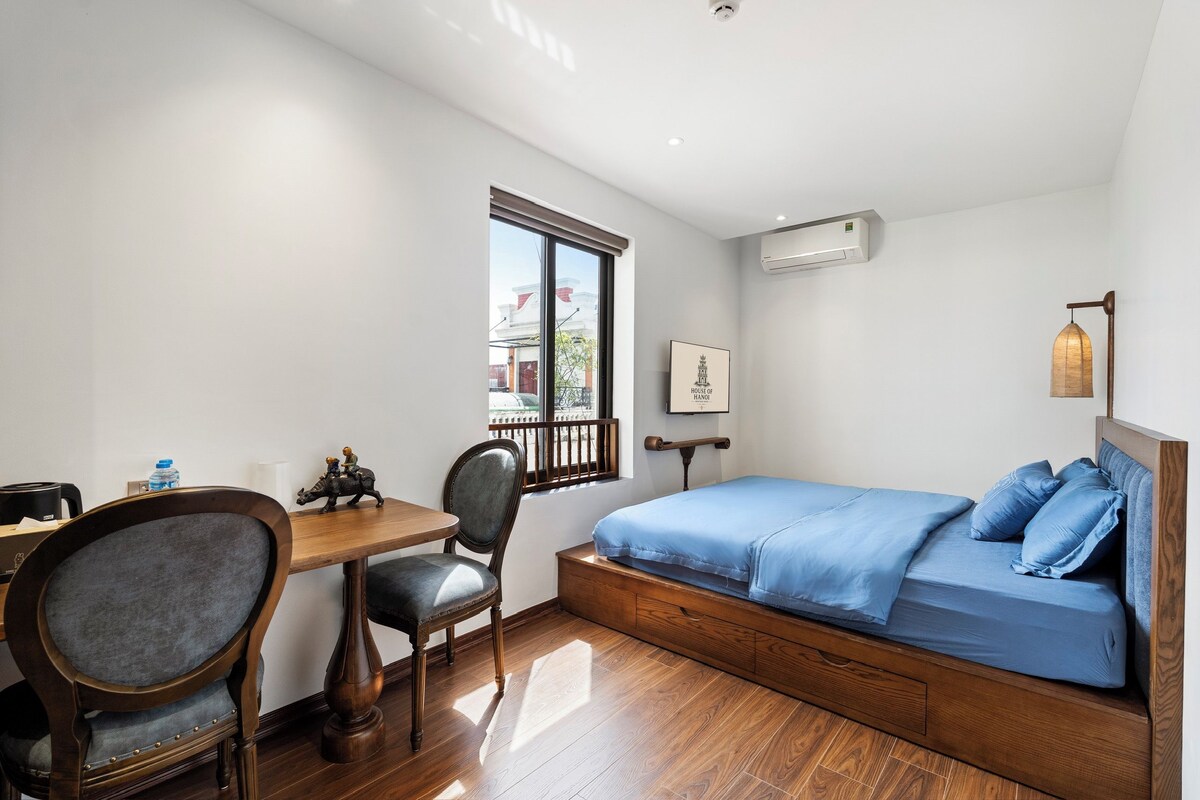 A bedroom with a bed, a desk, and a chair.