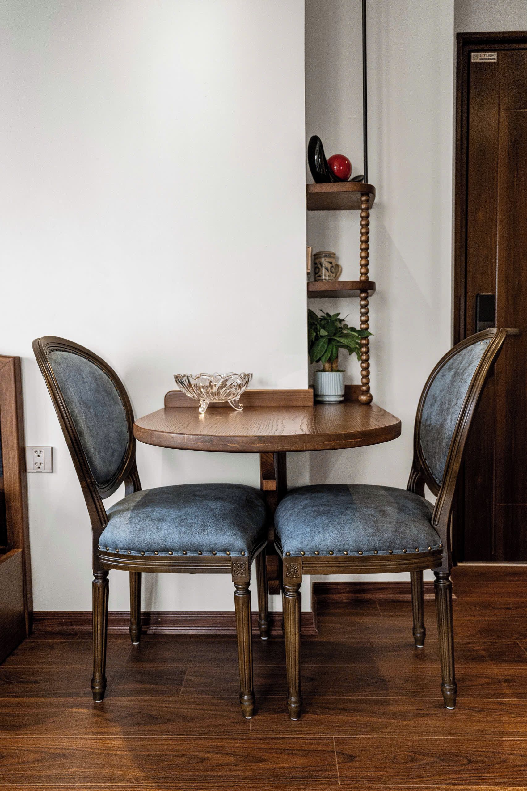 A dining table with two chairs, a bowl, and a potted plant on a wooden floor.