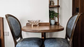 Una mesa de comedor con dos sillas, un bol y una planta en maceta sobre un piso de madera.