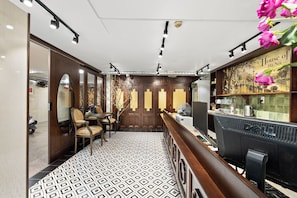 Rebost d'hotel amb un paviment estampat, mobiliari de fusta, una taula de recepció i una paret amb un panell decoratiu.