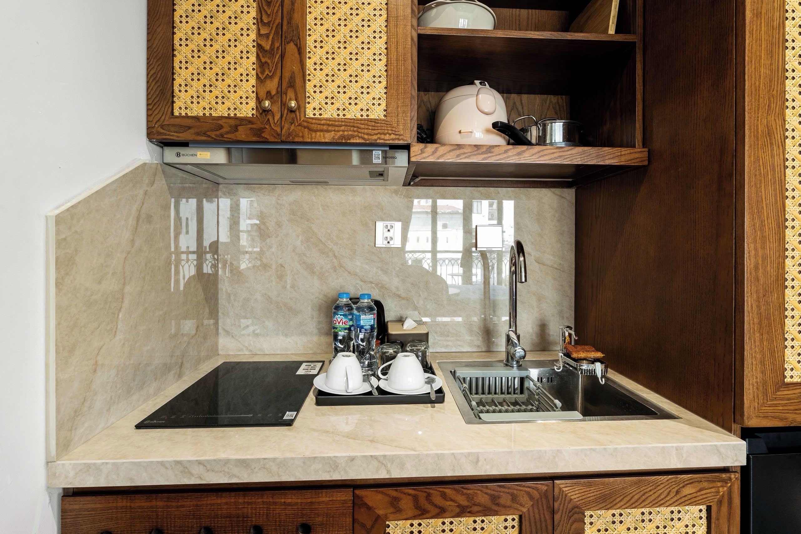 A kitchen with a marble countertop, a sink, a kettle, and a water dispenser.