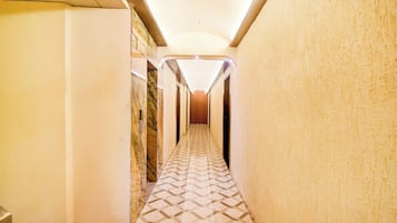 Un pasillo estrecho con pisos y paredes estampados, que conduce a una puerta al final.