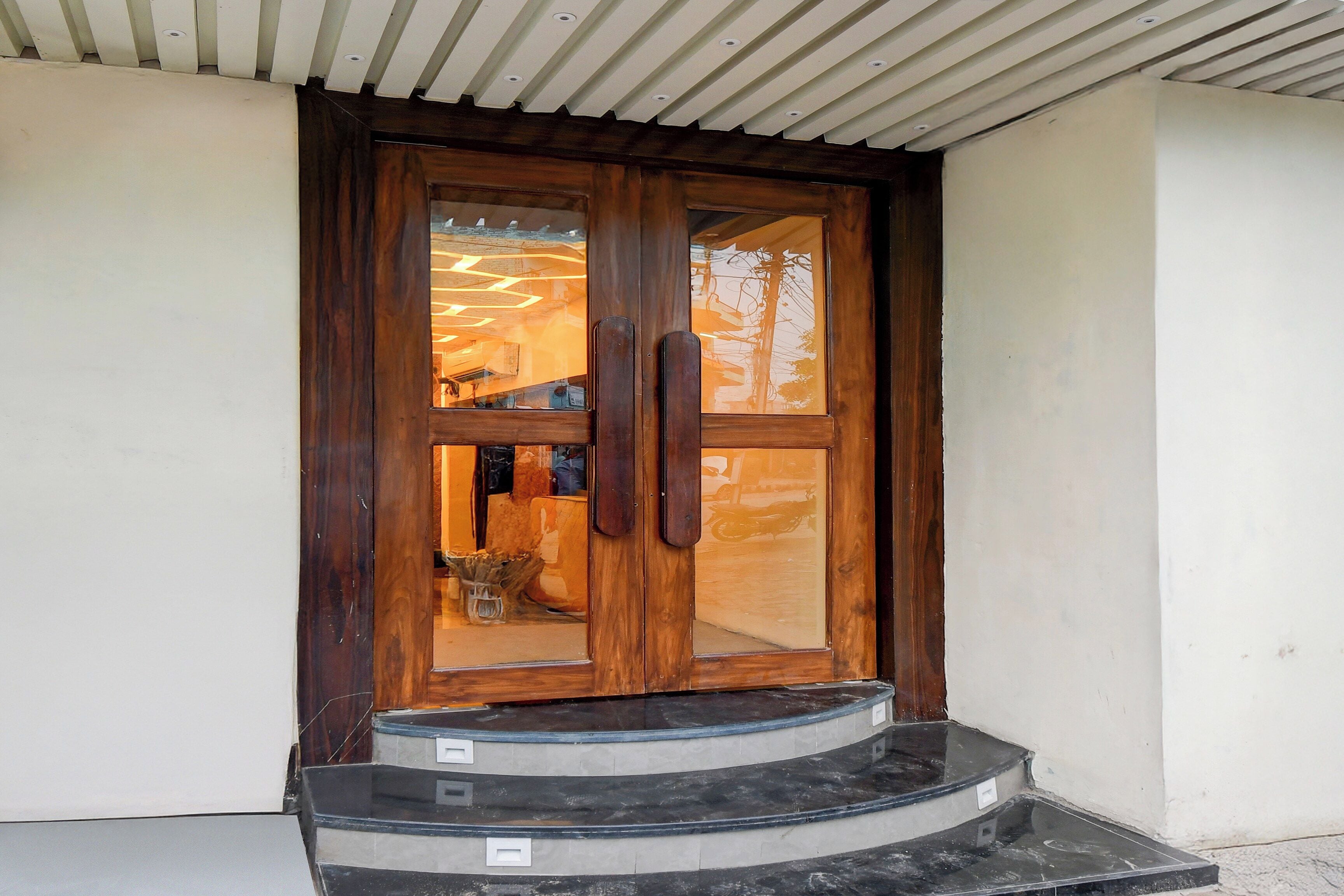 Une porte en bois avec des panneaux de verre et un escalier menant à cette porte.