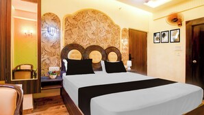 A hotel room with a large bed, a nightstand, a mirror, and a wall with decorative panels. - Super OYO Townhouse Varanasi Railway (Varanasi)