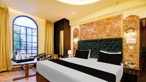 A hotel room with a large bed, a desk with a coffee maker, and a view of the outside through a window. - Super OYO Townhouse Varanasi Railway (Varanasi)