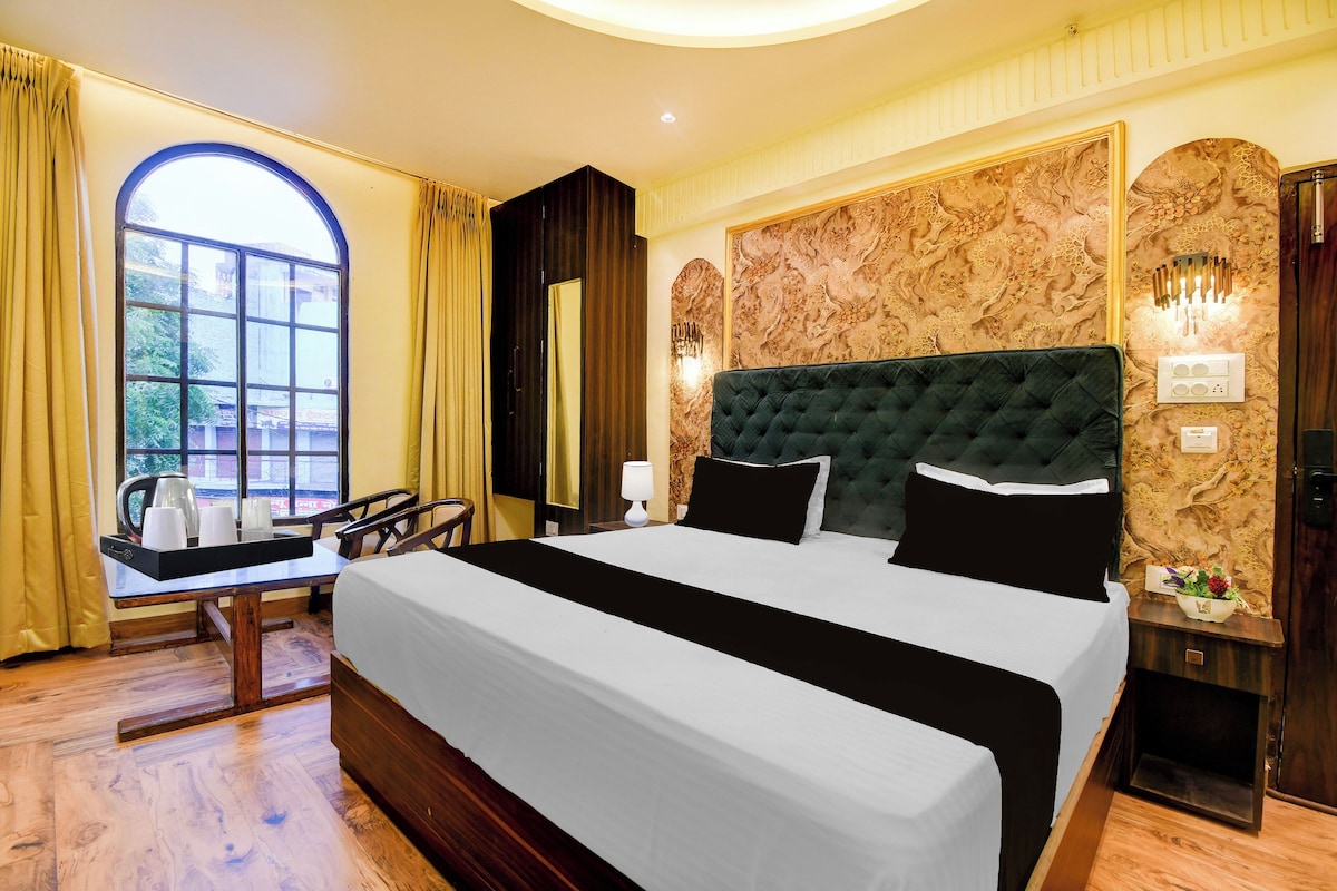 Ein Hotelzimmer mit einem großen Bett, einem Schreibtisch mit Kaffeemaschine und Blick ins Freie durch ein Fenster.