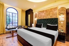 Ein Hotelzimmer mit einem großen Bett, einem Schreibtisch mit Kaffeemaschine und Blick ins Freie durch ein Fenster.