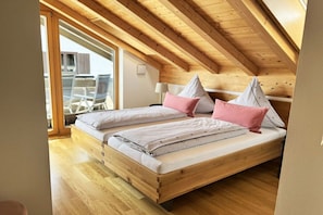 Quarto com teto de madeira, cama com roupa de cama listrada e vista para o exterior.