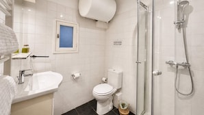 Moderni kylpyhuone, jossa on suihku, wc, pesuallas ja ikkuna.