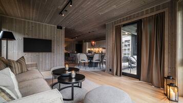 A modern living room with a sofa, a coffee table, and a TV mounted on the wall.