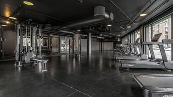Une salle de sport équipée de tapis de course, d’appareils de musculation et d’un mur recouvert de miroirs.