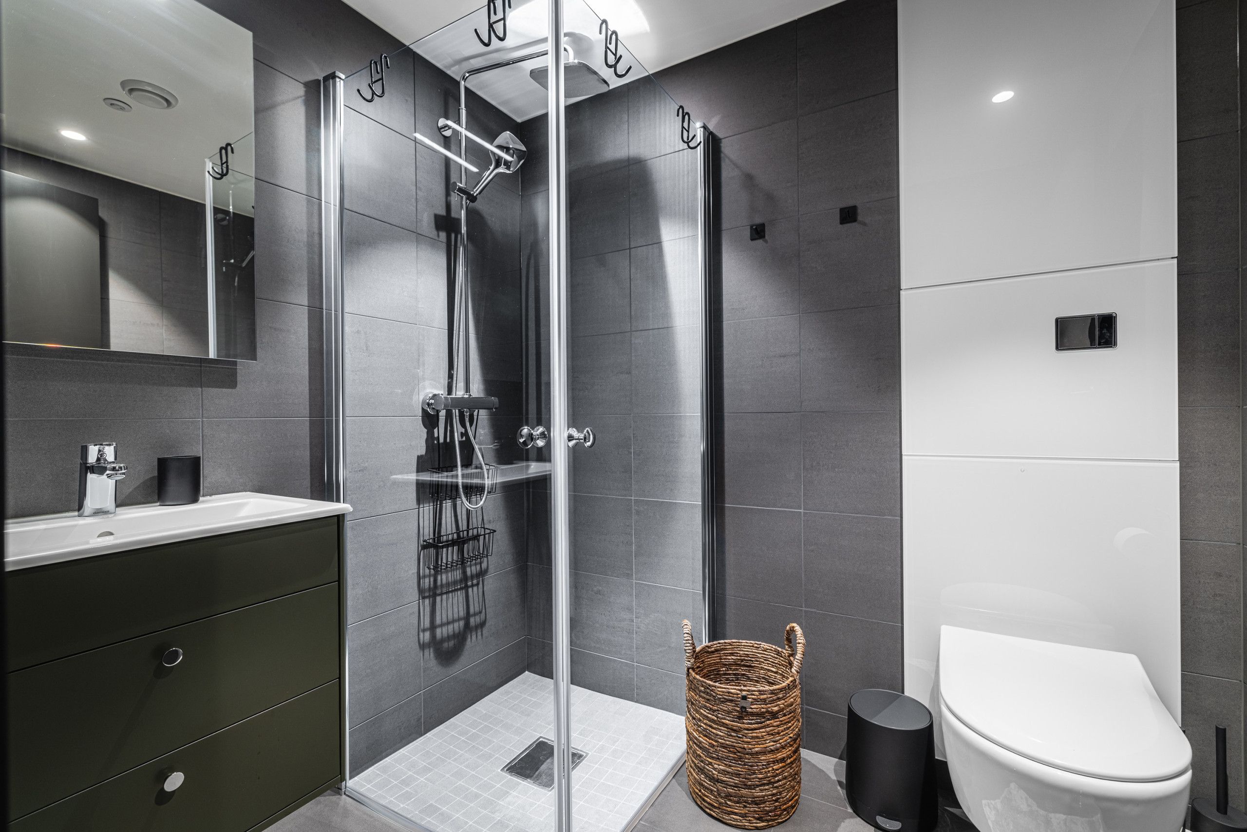 A modern bathroom with a glass-enclosed shower, a white toilet, and a dark-colored vanity.