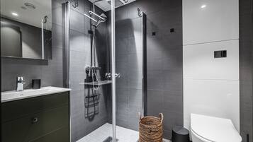 A modern bathroom with a glass-enclosed shower, a white toilet, and a dark-colored vanity.