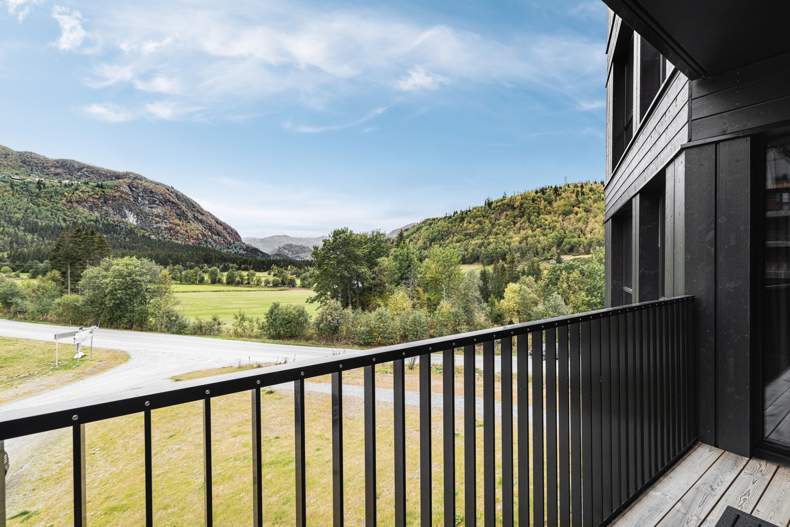 A balcony with a view of a mountainous landscape and a road.