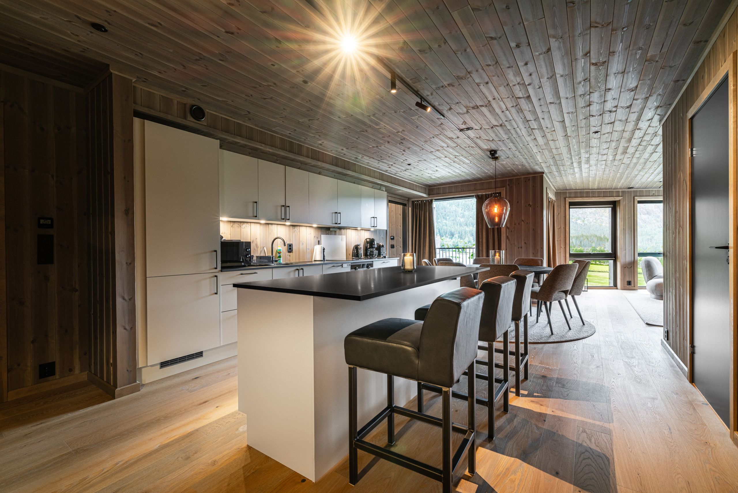 A modern kitchen with a central island, bar stools, and a view of the outdoors.