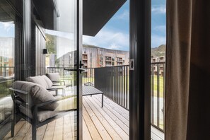 A balcony with a sofa and a table, overlooking a modern building and a mountainous landscape. - Exclusive Slopeside Living in Hemsedal (Hemsedal)