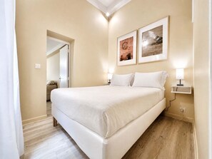 Une chambre d’hôtel avec un grand lit, deux lampes de chevet et deux tableaux encadrés au mur.