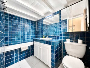 Une salle de bain avec des murs recouverts de carreaux bleus, un lavabo blanc et des toilettes.