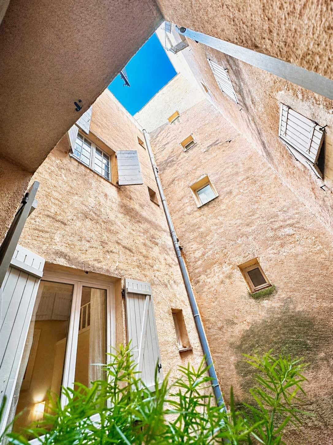 Un stretto vicolo tra edifici con persiane di legno e un cielo azzurro intenso.