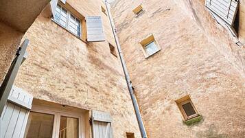 Un stretto vicolo tra edifici con persiane di legno e un cielo azzurro intenso.