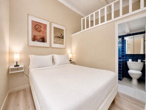 Une chambre à coucher avec un lit, deux lampes de chevet et deux tableaux encadrés accrochés au mur.
