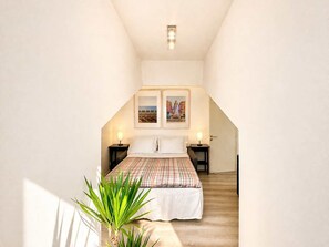 A bedroom with a bed, two bedside tables, a nightstand, a potted plant, and a picture on the wall. - Ersextius, GGB3, Nice (Nice)