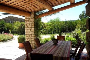 Eine Terrasse im Freien mit einer Steinwand, einer Holzbalkendecke und einem Tisch mit Stühlen.