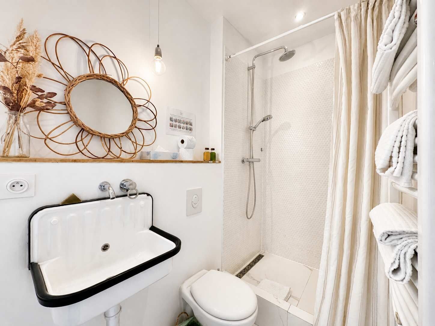 Ein modernes Badezimmer mit Waschbecken, Toilette und Dusche – alles in Weiß.