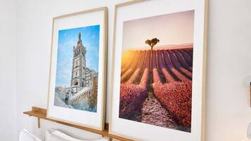 Twee ingekaderde foto's aan een muur, één toont een gebouw en de ander een veld met een boom.