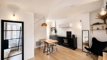 Een moderne keuken met een zwart aanrecht, een houten eettafel en een zwarte stoel.
