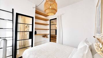 Une chambre à coucher avec un lit, une armoire et un luminaire suspendu.