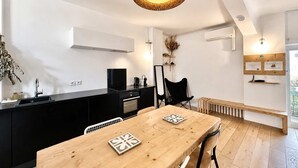 A modern kitchen with a black countertop, a wooden dining table with two chairs, and a hanging woven light fixture. - Ersextius, LMR2, Aix-en-Provence (Aix-en-Provence)