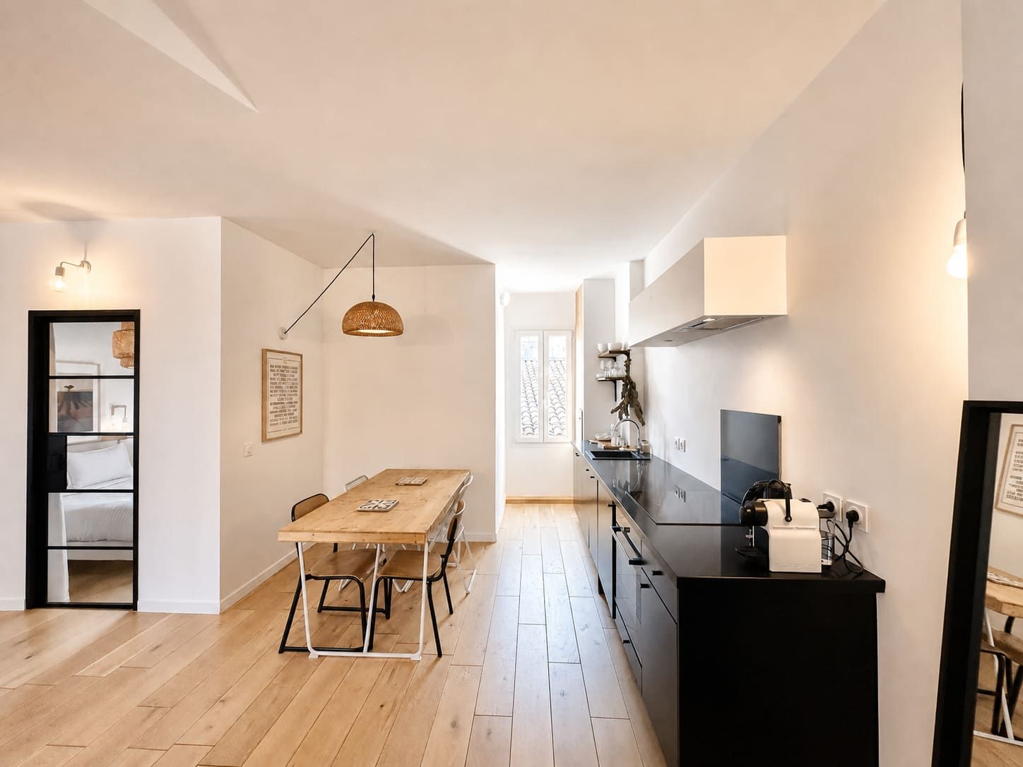 Een moderne keuken met een zwart aanrecht, een houten eettafel en hanglampen.