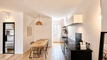 Een moderne keuken met een zwart aanrecht, een houten eettafel en hanglampen.